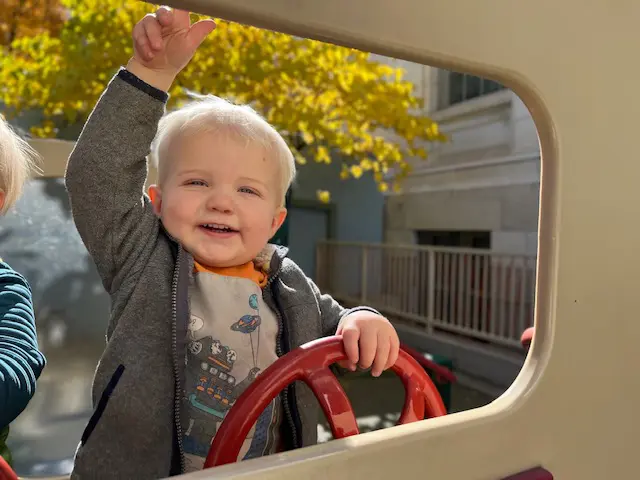 Toddler smiling holding car steering